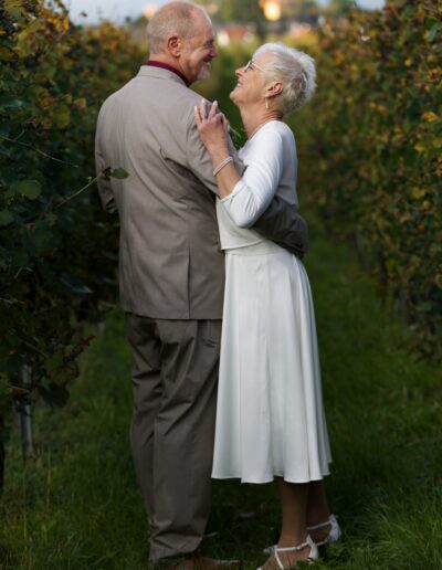 Das Brautpaar tanzt innig zwischen Weinreben, umgeben von spätsommerlicher Abendsonne – ein Moment voller Ruhe und Liebe. Hochzeit im Freien, Paarshooting im Weinberg, reife Liebe, romantische Stimmung, Naturhochzeit.