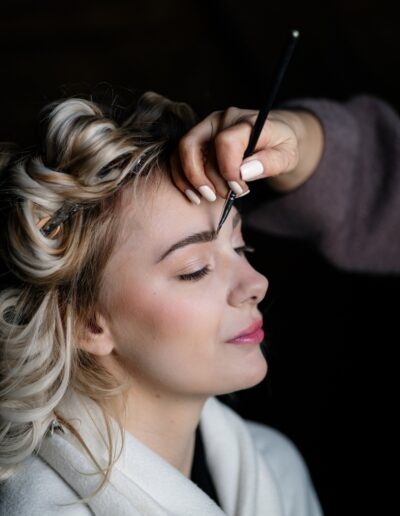 Eine Braut lässt sich am Hochzeitstag professionell schminken – ihr Blick entspannt, während das Augen-Make-up finalisiert wird. Getting Ready, Brautstyling, Hochzeitsporträt, Braut Make-up, Vorbereitung Hochzeit.