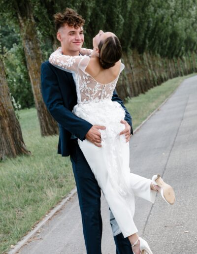 Verspielter Moment eines Brautpaares beim Spaziergang – er hebt sie hoch und sie lacht. Hochzeitsfotografie Lahr mit Persönlichkeit.