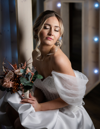 Eine Braut sitzt umhüllt von LED Lichtern. Ihre Augen sind geschlossen. In der Hand hat sie einen Brautstrauss. das Gesicht ist zum Licht gedreht.