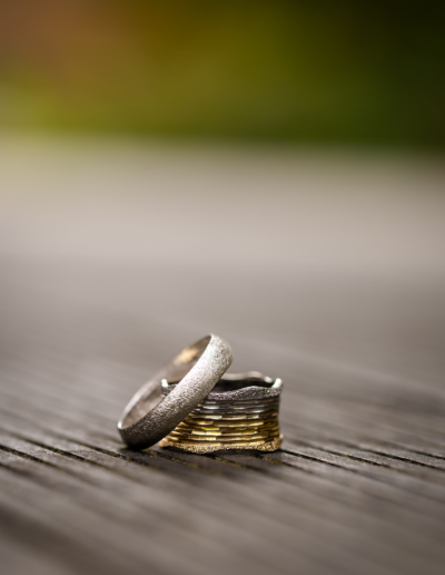 Brautpaar Ringe in Großaufnahme, liegen auf einem Holzboden, ein Ring am anderen angelehnt.